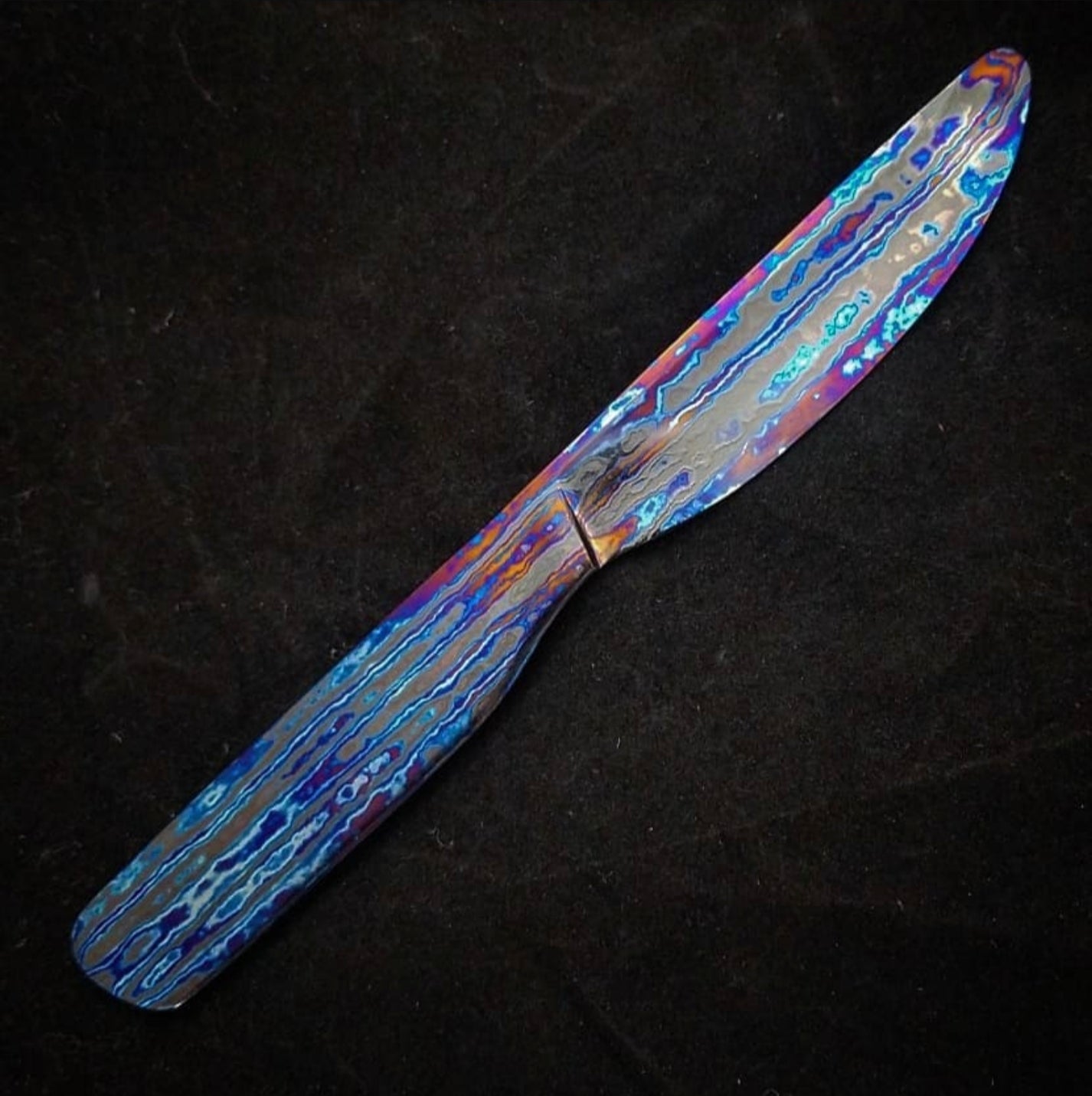 Close-up of handcrafted Black Timascus art piece with iridescent layered patterns by Larevo Customs.